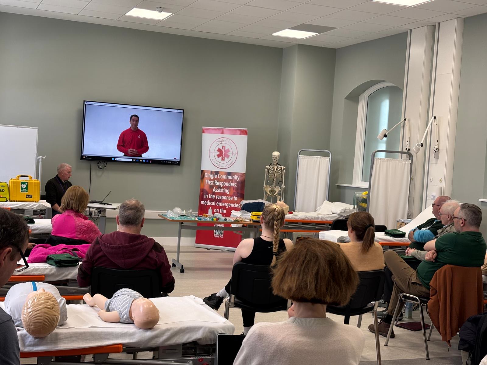 Trainees seated in a hall watching a presentation at a Dingle Heart Safe training session, with training manikins in the foreground