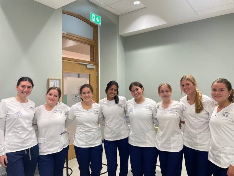 Eight nursing students in white tunics who helped run the practical training